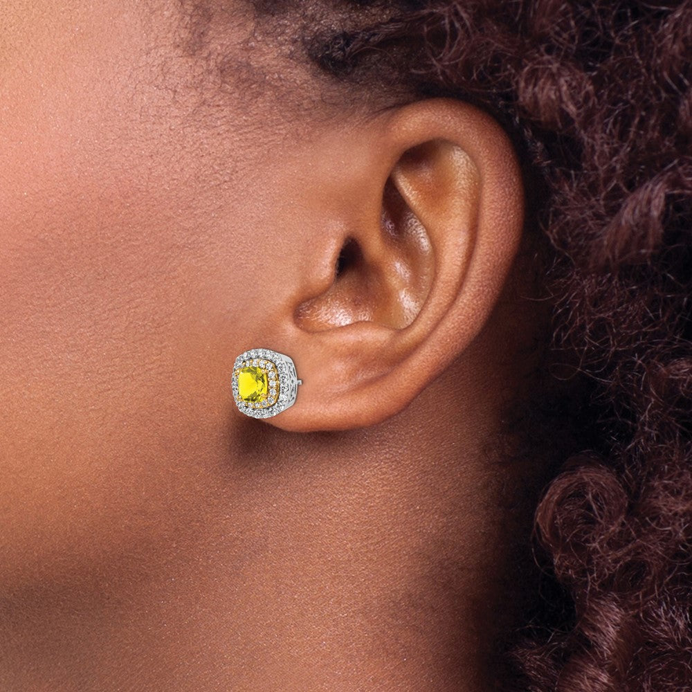 Close-up of an ear wearing a yellow gemstone earring with a blurred background