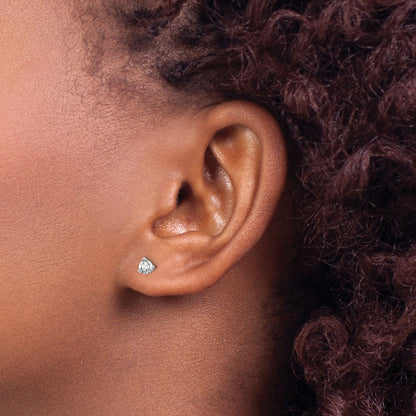 Close-up of an ear wearing a diamond earring with hair styled in braids.