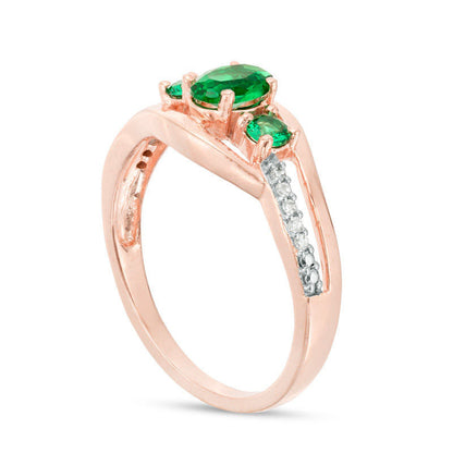 Oval Lab-Created Emerald and 0.05 CT. T.W. Diamond Three Stone Bypass Engagement Ring in Solid 10K Rose Gold
